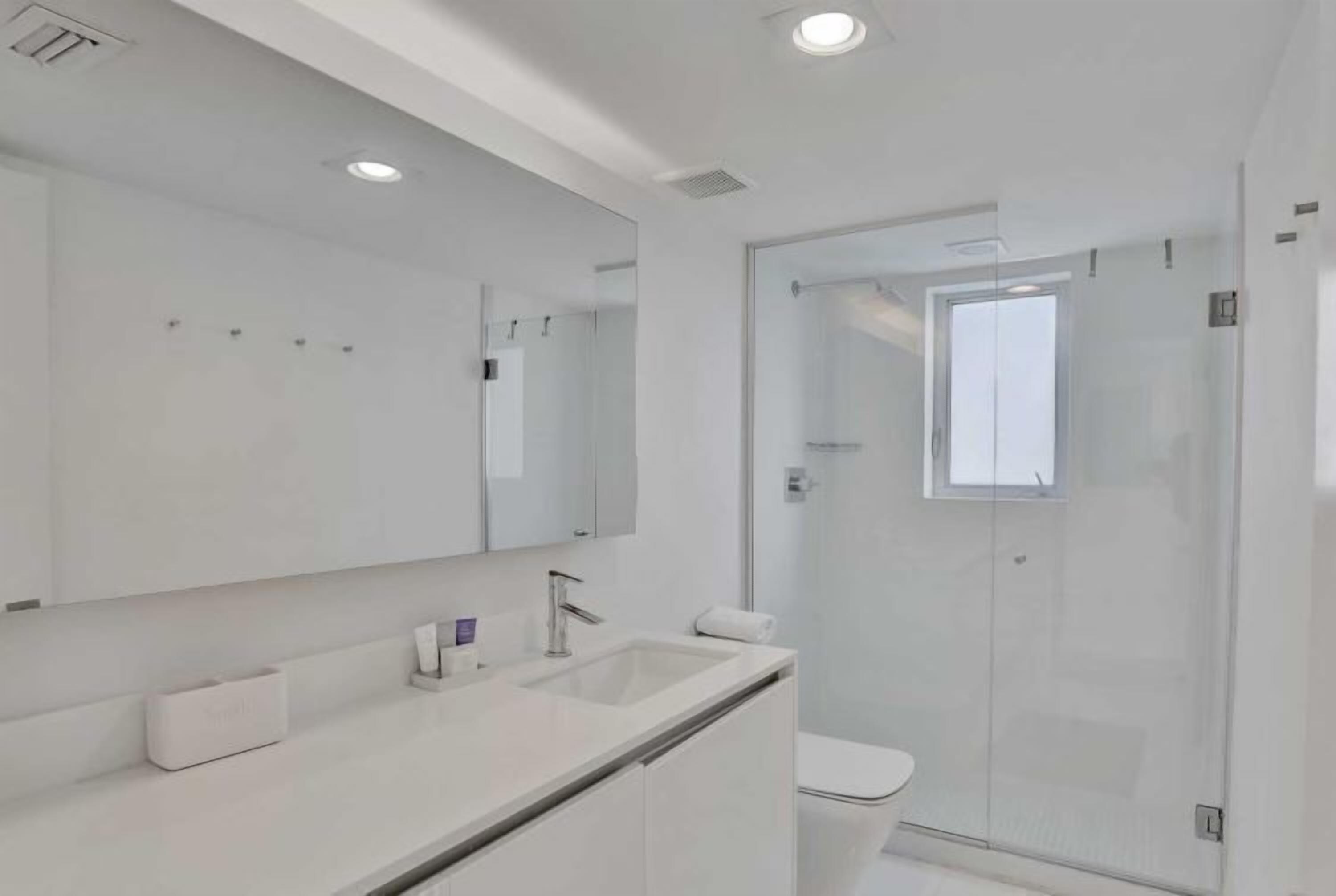 Une salle de bain moderne avec un grand miroir, un lavabo et une douche à parois de verre.