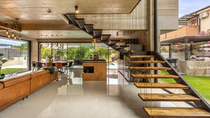 Eine moderne Küche mit Kochinsel, ein Essbereich mit einer Couch und eine Treppe zu einem Außenbereich.