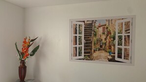 Een kamer met een raam dat uitzicht biedt op een smalle steeg met trappen en groen.