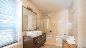 Un baño moderno con un espejo grande, dos lavamanos, una ducha y un inodoro.