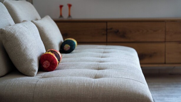Un sofá con cojines y un aparador de madera en una habitación.