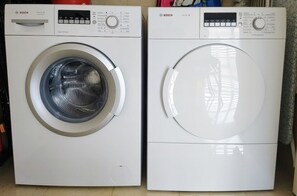 Two white Bosch washing machines, one with a control panel and the other with a digital display. - Stylish 2BR Tel Aviv • Luxury & Ease by SeaNRent (Tel Aviv-Yafo)