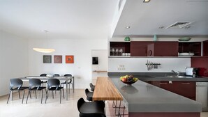Cocina moderna con una isla central, comedor con sillas y un lavamanos visible.