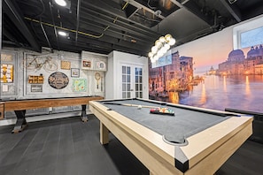 A pool table in a room with a large mural of a cityscape and a billiards-themed wall.
