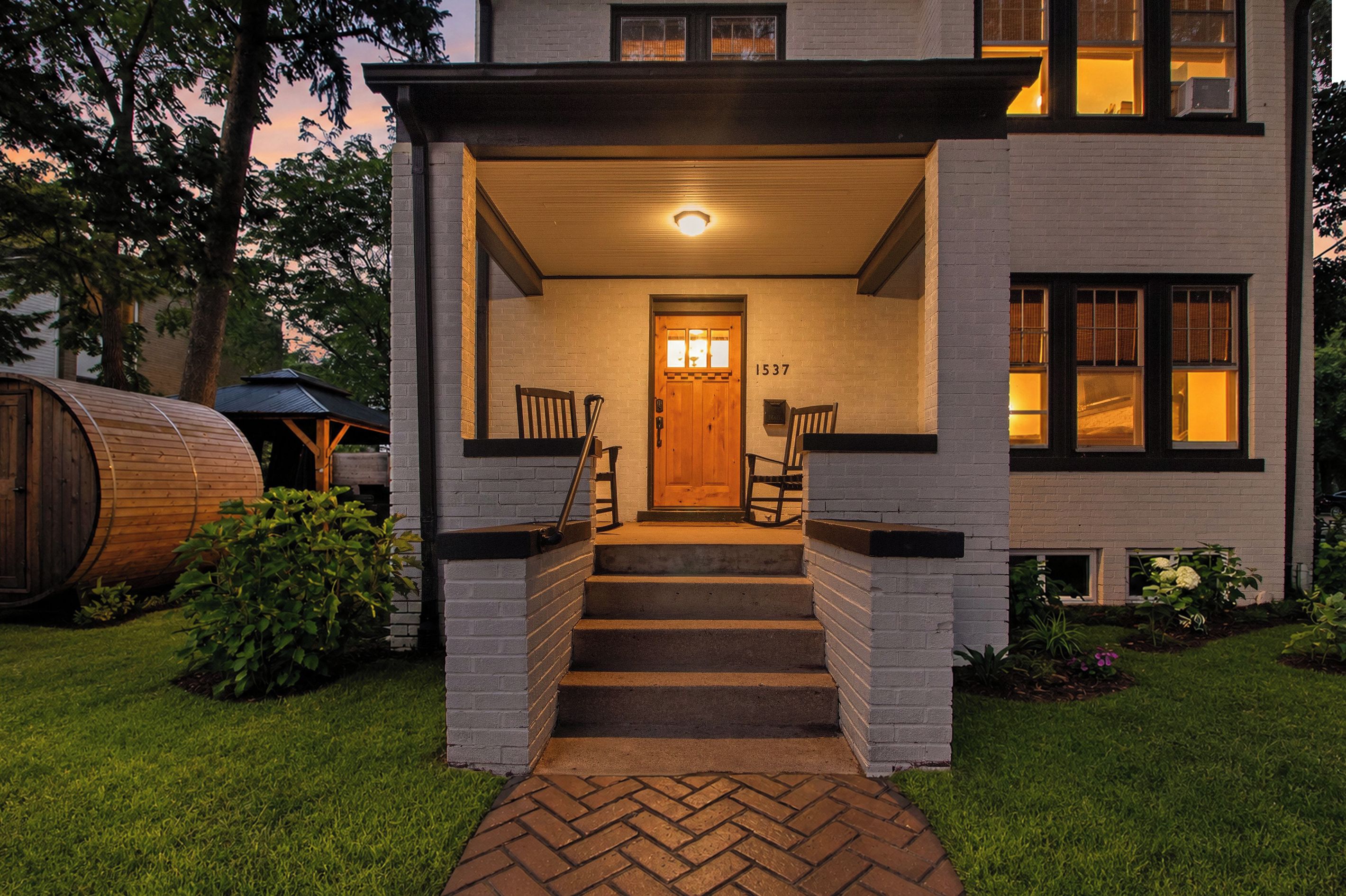 A two-story house with a front porch, a wooden door, and a number '1537' on the wall.
