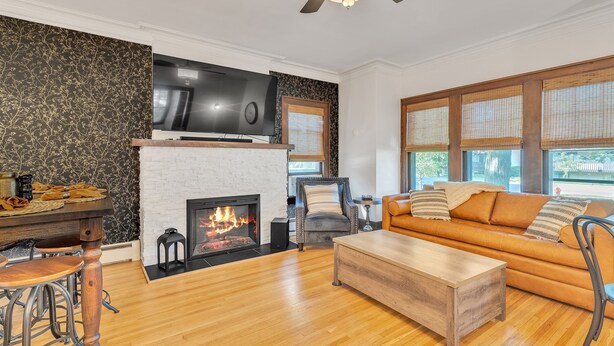 Una sala de estar con chimenea, un sofá, una mesa de centro y un televisor montado en la pared.