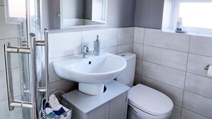 Une salle de bain moderne avec un lavabo blanc, des toilettes et une douche à parois de verre.