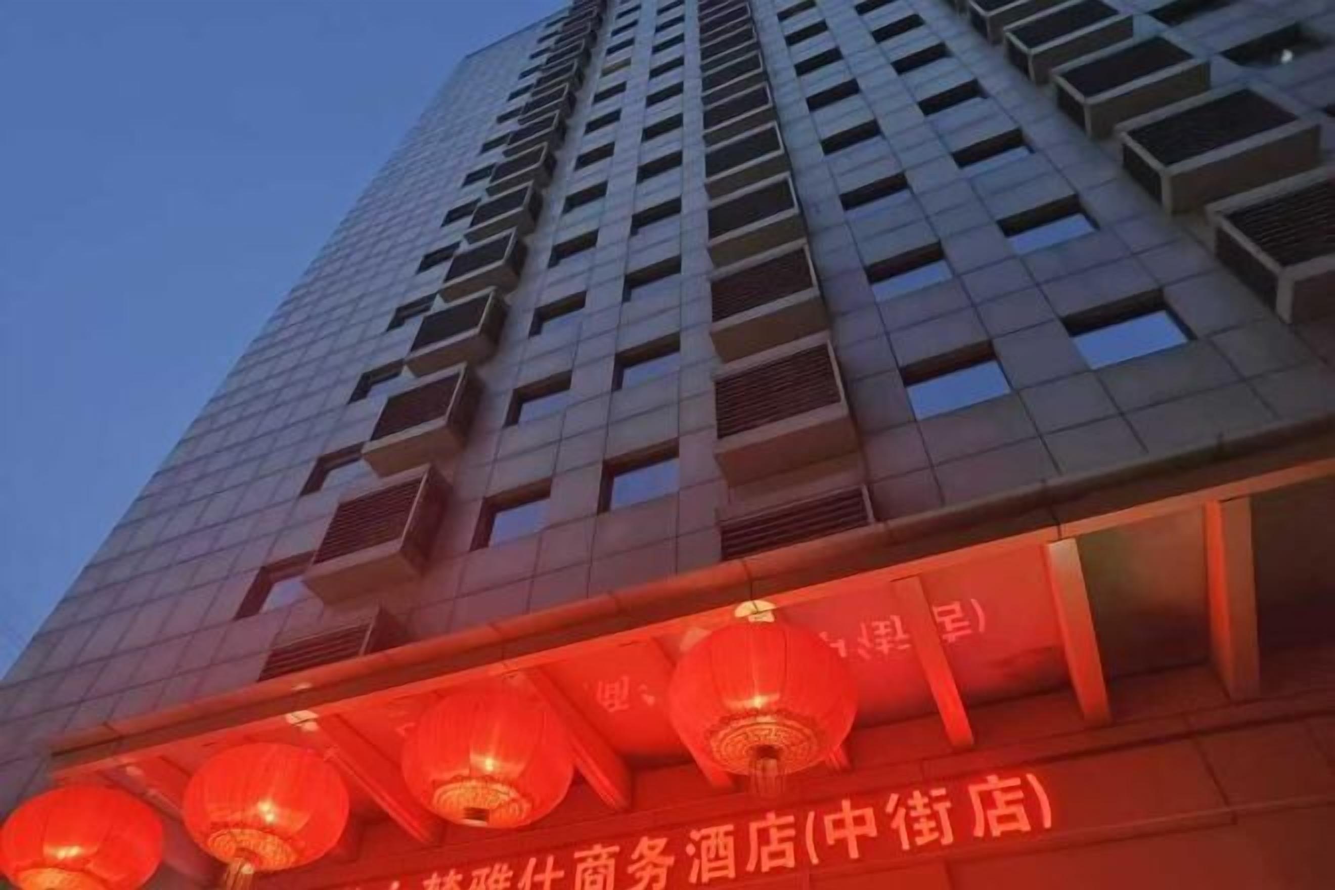 A tall building with a commercial space on the ground floor, featuring a row of red lanterns and a sign in Chinese characters.