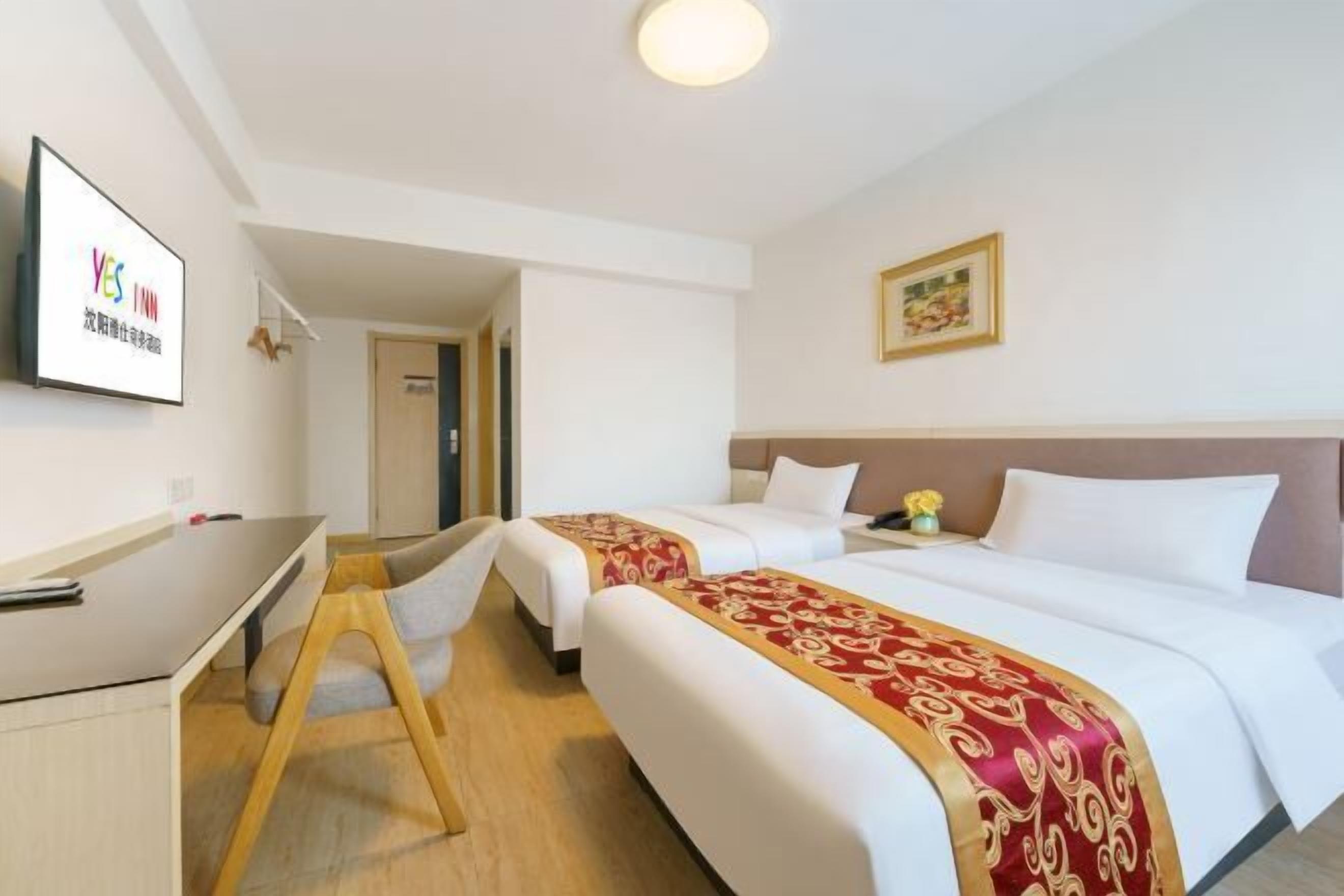 A hotel room with two beds, a desk, and a chair.