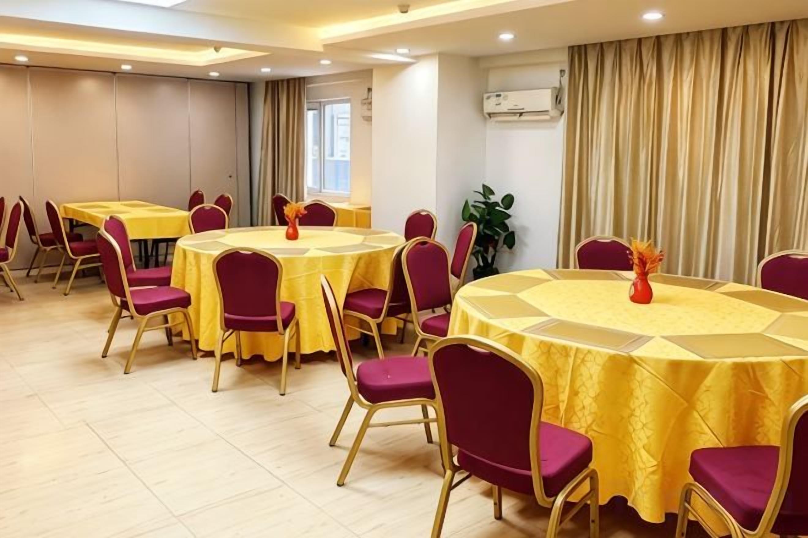 Un salón de conferencias con varias mesas redondas, cada una cubierta con un mantel amarillo y rodeada de sillas púrpuras.