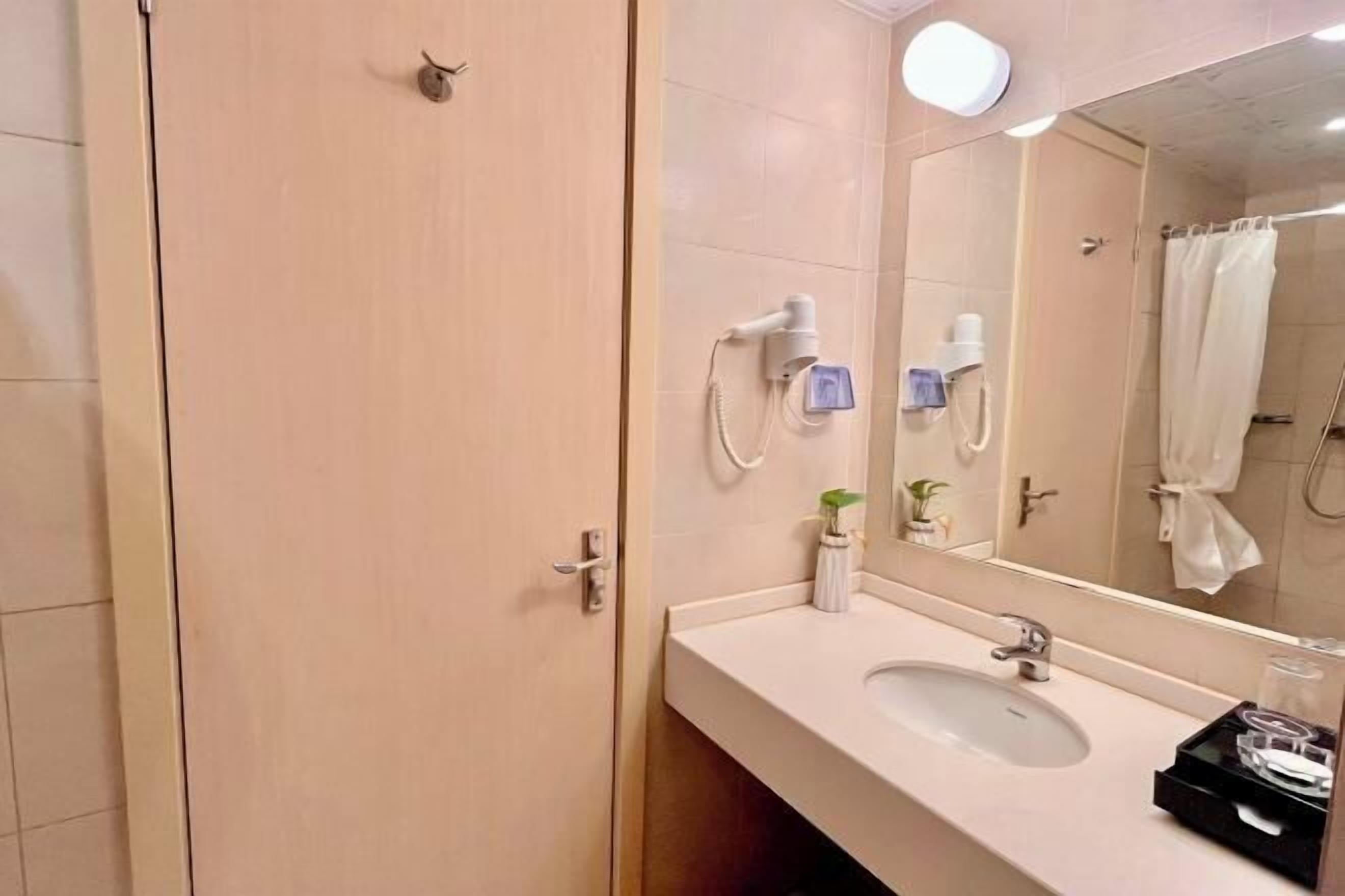 A bathroom with a sink, mirror, towel rack, and a shower area.