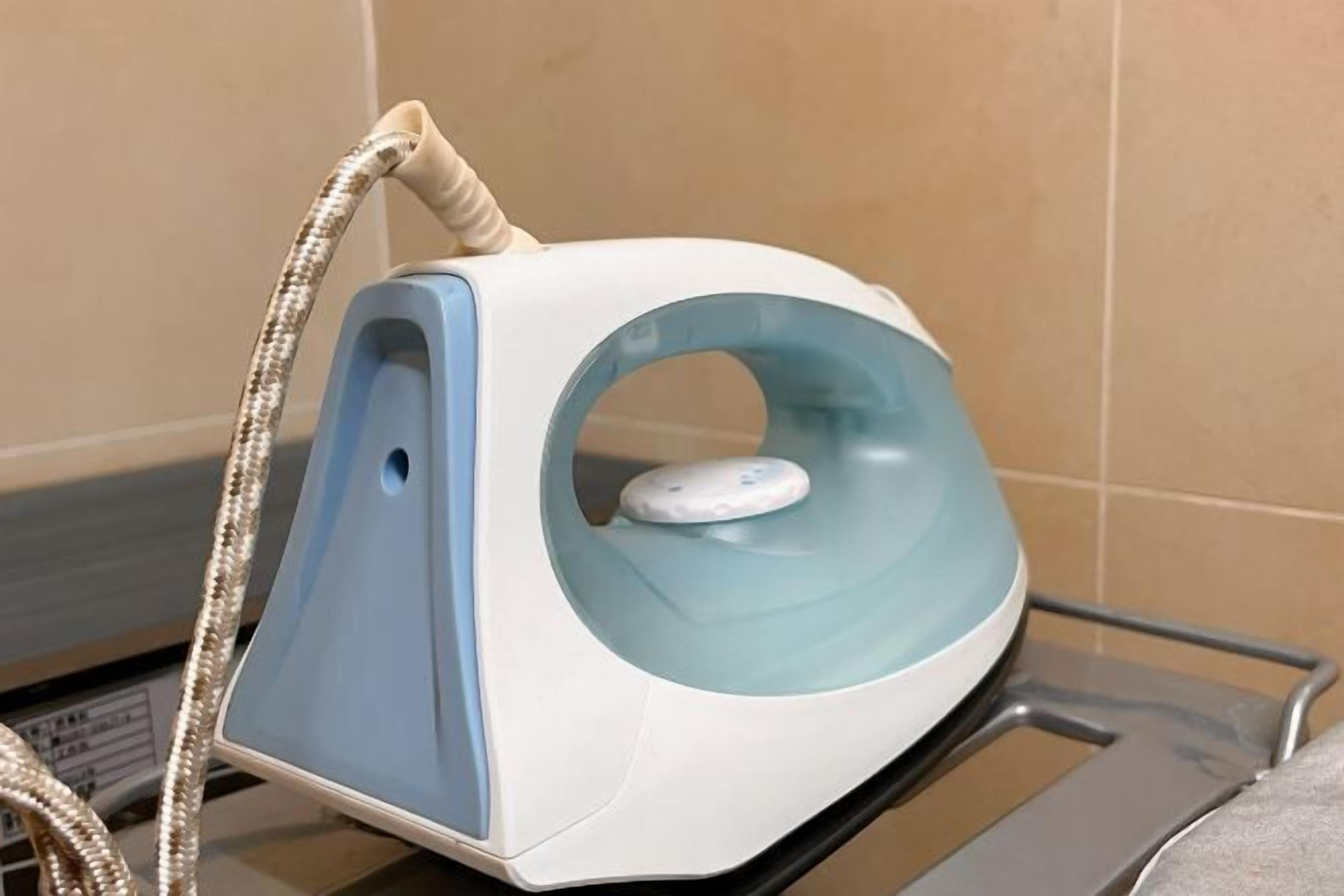 A white and blue iron with a cord, placed on a metal rack.