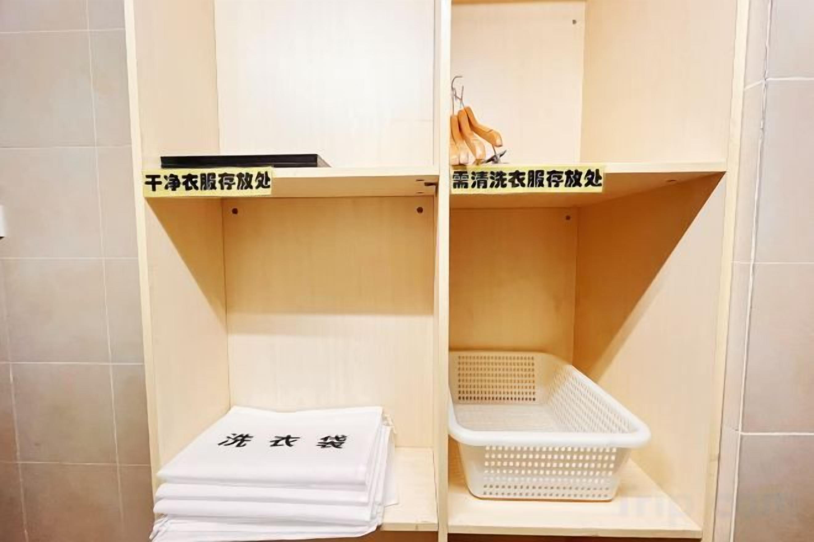 A hotel room with a shelf containing folded towels and a basket.