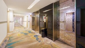 A hotel corridor with a patterned carpet, a modern elevator, and a trash bin. - Longemont Yashi Business Hotel (Zhongjie Street，Shenyang) (Shenyang)