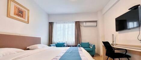 A hotel room with a bed, a desk, a chair, a television, and an air conditioning unit.