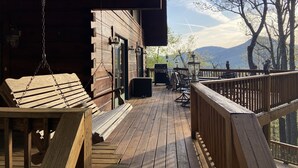 Een houten terras met een hekwerk, een barbecue en een bank.