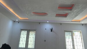 A room with a white ceiling featuring recessed lighting and a central circular light fixture. There are two windows with metal bars and a door with a similar design. - Elegantly Apportioned 4-bed House in Ikorodu (Ikorodu)