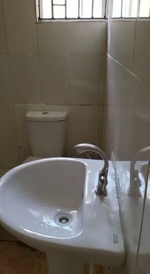 A bathroom with a white sink, a toilet, and a window with bars. - Elegantly Apportioned 4-bed House in Ikorodu (Ikorodu)