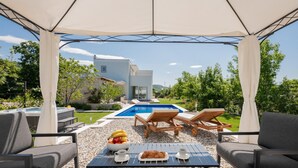 A covered outdoor area with a pool, lounge chairs, and a table with food and drinks. - Awesome home in Veliki Brocanac (Veliki Brocanac)