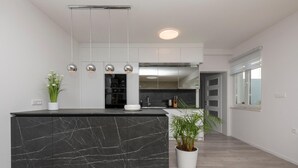 A modern kitchen with a marble island, pendant lighting, and a view into the dining area. - Awesome home in Veliki Brocanac (Veliki Brocanac)