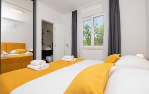 Habitación de hotel con dos camas, baño y ventana con cortinas.