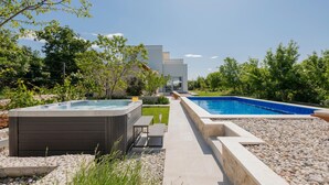 A modern outdoor pool area with a hot tub, a patio with seating, and a view of a contemporary building in the background. - Awesome home in Veliki Brocanac (Veliki Brocanac)