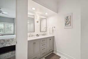 A modern bathroom with a large mirror, two sinks, and a towel rack.