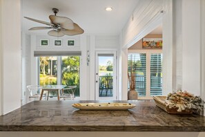 A kitchen with a marble countertop, a ceiling fan, and a view of the outdoors.