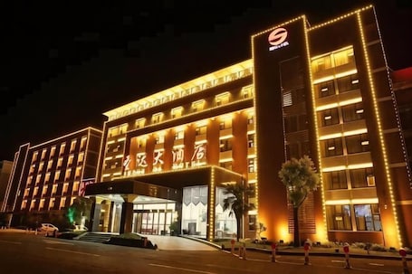 A multi-story hotel with a prominent entrance, illuminated signage, and a well-lit facade.. Sheng Da Hotel