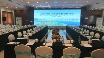 A conference room with a long table, chairs, and a presentation screen.