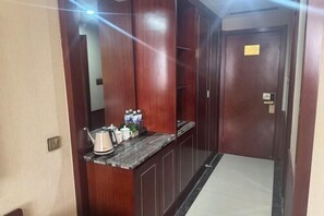 A hotel room with a wooden vanity, a marble countertop, and a door with a lock.