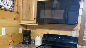 A kitchen with wooden cabinets, a black stove, a microwave, and a coffee maker. - Bearadise in the Red, Wifi, Hot Tub, great proximity to Red River Gorge (Campton)
