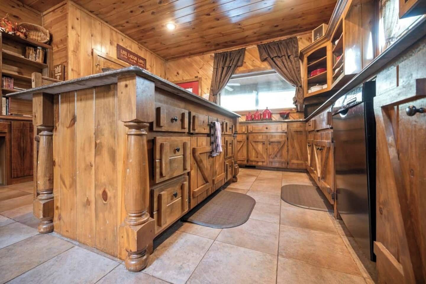 A wooden kitchen with built-in cabinets, a central island, and a refrigerator.
