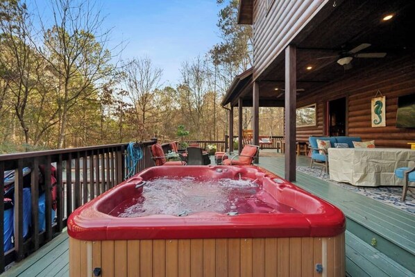 A hot tub on a wooden deck with outdoor furniture and a covered area. - Country Cabana -Swimming Pool/Hot Tub/Sleeps 10 (Broken Bow)