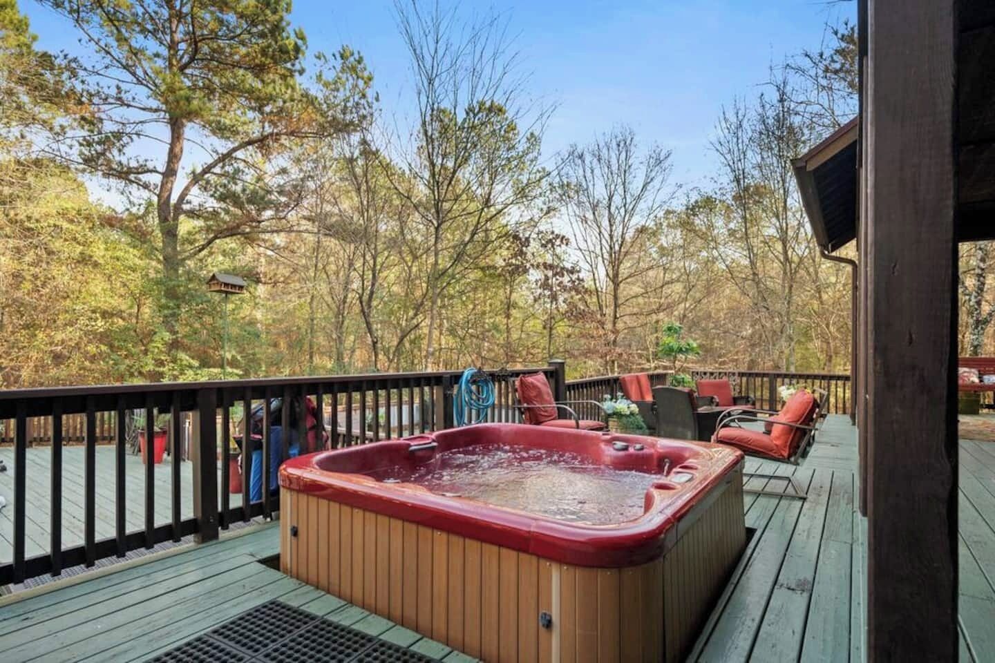 A wooden deck with a hot tub, outdoor furniture, and a view of trees.