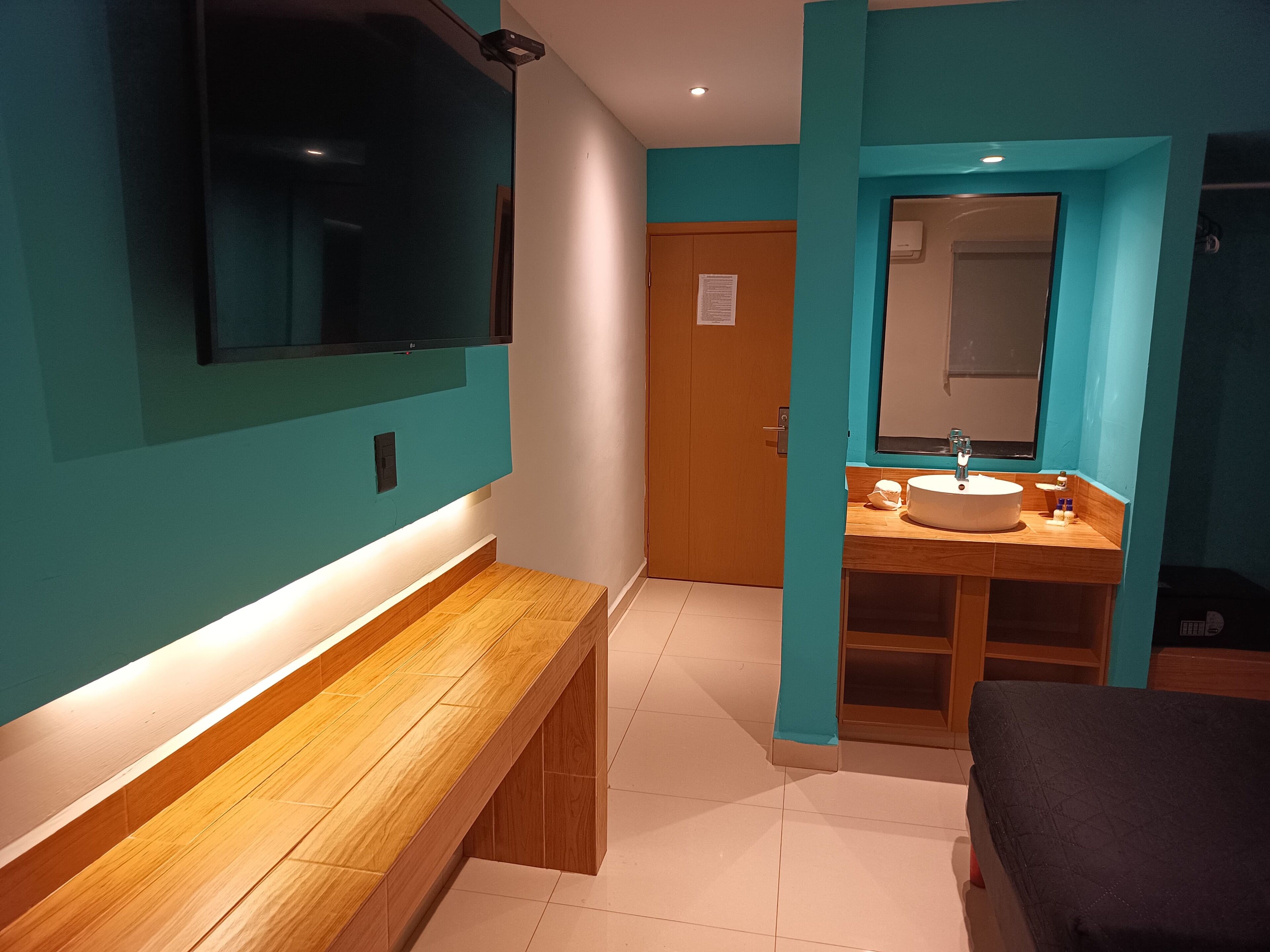A modern bathroom with a wooden bench, a sink, and a mirror.