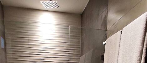 Un baño moderno con ducha de vidrio, inodoro y perchero para toallas.