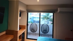 Ein modernes Zimmer mit Balkon, Fernseher, Schreibtisch und zwei Stühlen.