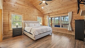 Un dormitorio con paneles de madera, una cama, mesitas de noche y ventanas.