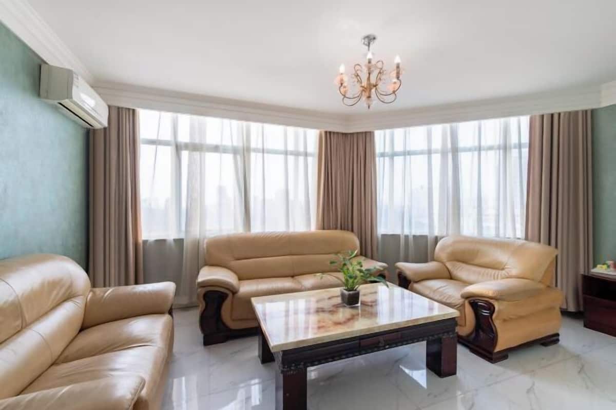 A room with leather sofas, a marble coffee table, and a chandelier.