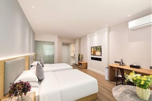 Une chambre d’hôtel moderne, équipée de deux lits, d’un bureau, d’une chaise, d’une petite table et d’une plante en pot.