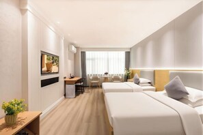 Habitación de hotel con dos camas, un escritorio, un televisor y una ventana con cortinas.