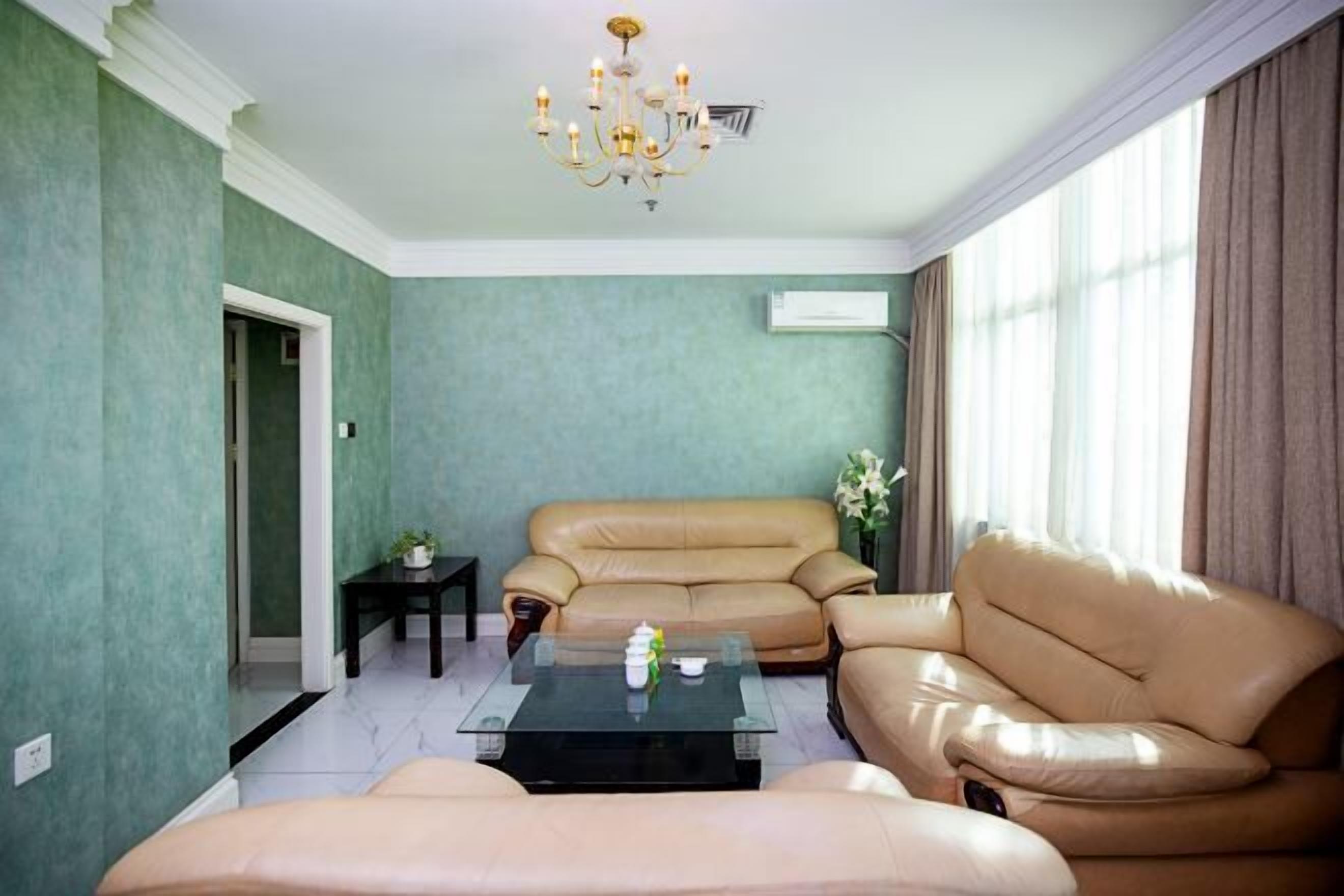 Una sala de estar con un sofá color beige, una mesa de centro de vidrio y una araña.