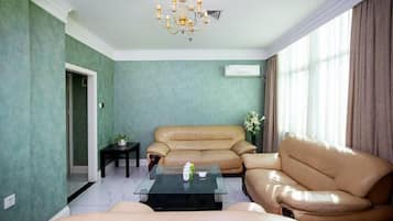 Una sala de estar con un sofá color beige, una mesa de centro de vidrio y una araña.