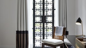 A room with a large arched window, a chair, a desk with a lamp, and a herringbone-patterned floor. - Casa Polanco Hotel Boutique (Mexico City)