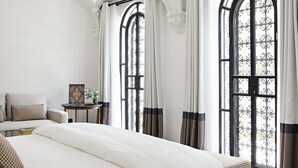A bedroom with a large bed, two windows with curtains, a small table with a vase, and a decorative ceiling. - Casa Polanco Hotel Boutique (Mexico City)