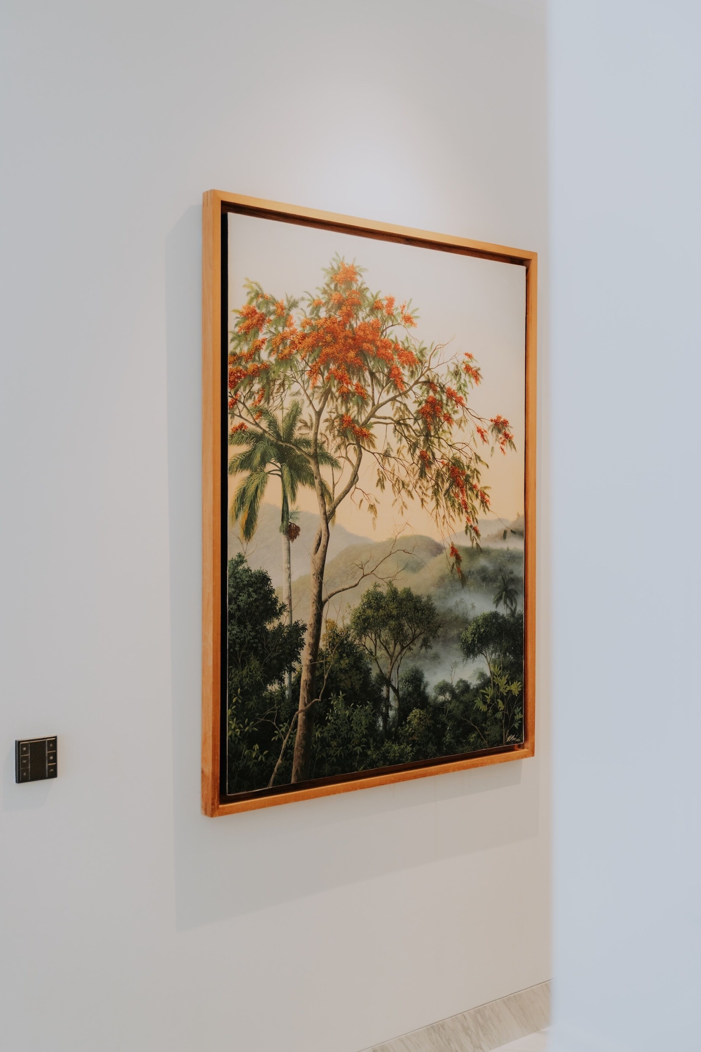 A framed painting of a tree with orange flowers on a wall.