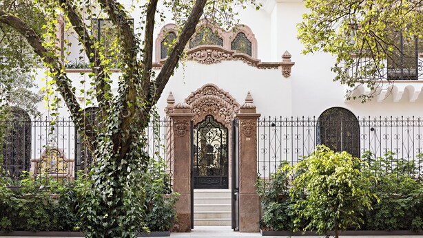 A gated entrance with a wrought iron gate, a stone archway, and a pathway leading to a building with ornate architectural details. - Casa Polanco Hotel Boutique (Mexico City)