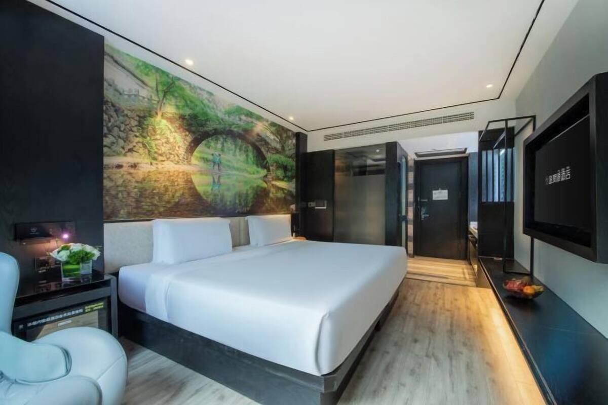 Un dormitorio moderno con una cama grande, un televisor montado en la pared y un mural con una escena de bosque.