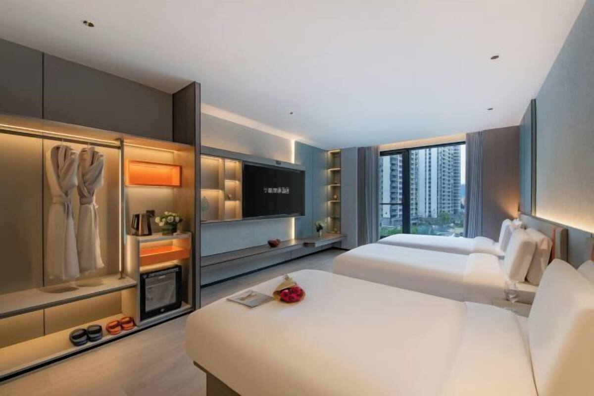 Una habitación de hotel moderna con una cama grande, televisor, armario y vistas a la ciudad.